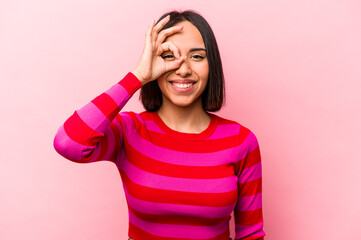 Young hispanic woman isolated on pink background excited keeping ok gesture on eye.