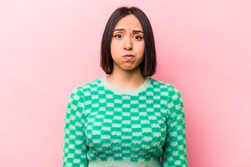 Fototapeta premium Young hispanic woman isolated on pink background blows cheeks, has tired expression. Facial expression concept.