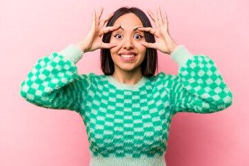 Young hispanic woman isolated on pink background keeping eyes opened to find a success opportunity.