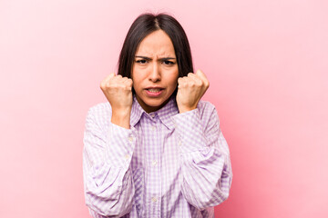 Young hispanic woman isolated on pink background upset screaming with tense hands.