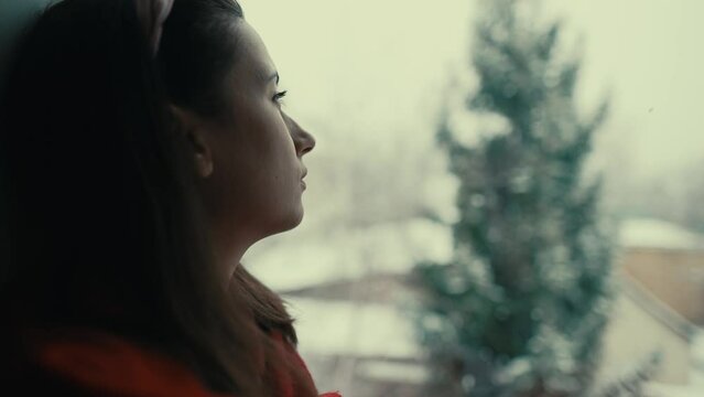 Sad woman sitting on windowsill in winter