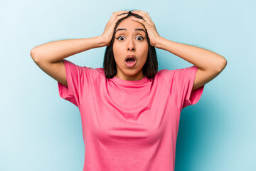 Young hispanic woman isolated on blue background surprised and shocked.