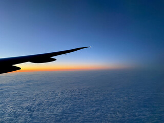 Airplane wing silhouette with an orange blue sky sunset