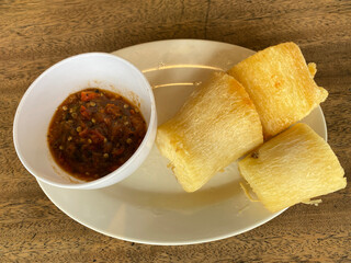Slices of fried cassava and chili sauce on a white plate. Focus selected