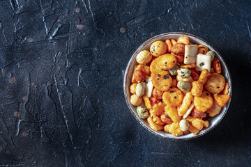 Fototapeta premium Japanese rice crackers in a bowl on a black slate background, shot from the top with copy space