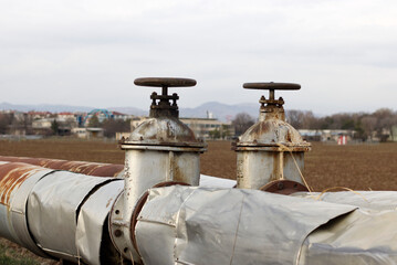 An old rusty pipeline in the land with valves.