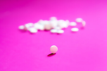 Assorted pharmaceutical medicine pills, tablets and capsules and bottle on pink background. Copy space for text
