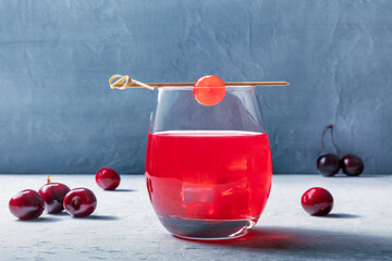Cocktail with cherry and ice, an aperitif with a garnish and fresh berries, a summer cold drink
