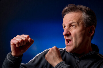 A middle aged white man in boxing stance on a black and blue background