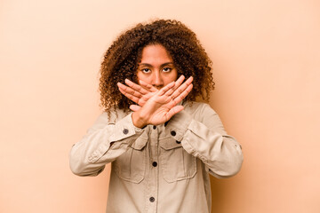 Young African American woman isolated on beige background doing a denial gesture