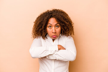 Young African American woman isolated on beige background shrugs shoulders and open eyes confused.