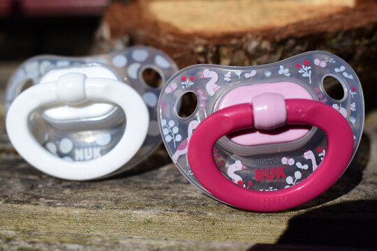 Schnuller von Nuk in Wei&szlig; und Rosa auf Holz in der Sonne f&uuml;r outdoor und unterwegs, Babyartikel	

