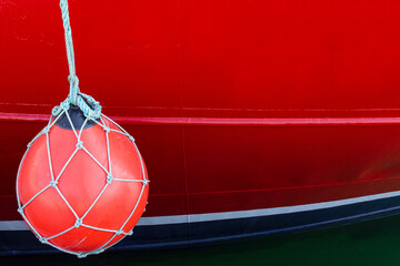 red fishing boat and buoy on port side