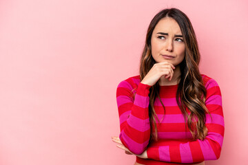 Young caucasian woman isolated on pink background looking sideways with doubtful and skeptical...