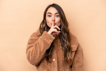 Young caucasian woman isolated on beige background keeping a secret or asking for silence.