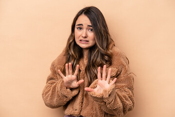 Young caucasian woman isolated on beige background rejecting someone showing a gesture of disgust.