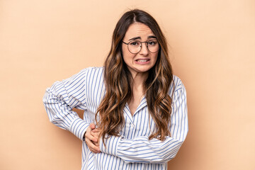 Young caucasian woman isolated on beige background having a liver pain, stomach ache.