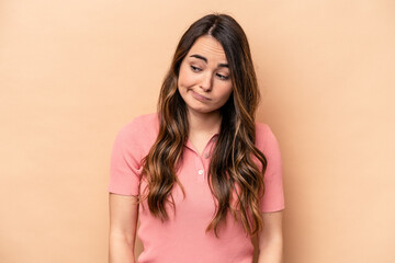 Young caucasian woman isolated on beige background shrugs shoulders and open eyes confused.