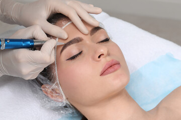 Young woman during procedure of permanent eyebrow makeup in beauty salon, closeup - obrazy, fototapety, plakaty