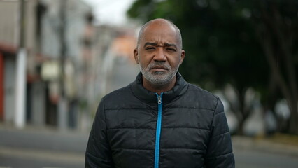 Portrait of a serious senior black man standing outside in street looking at camera