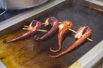 Tentacoli di polipo in cottura sulla piastra rovente professionale di un ristorante