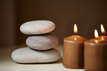 Fototapeta na wymiar Natural therapy. Three stones balanced on top of each other alongside some candles.
