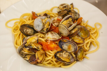 Piatto di spaghetti con sugo di vongole e pomodori servito in un ristorante elgante