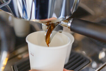 Caffè mentre esce da una macchina professionale di un bar e cade in un bicchiere di carta riciclabile da asporto 