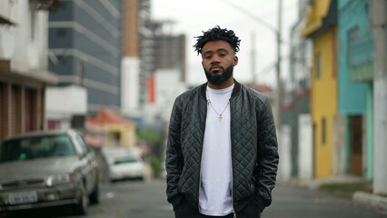 A young black man standing outside in street looking at camera an African American person portrait