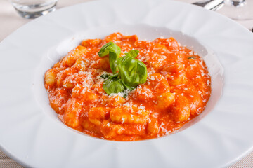 Piatto di gnocchi alla Sorrentino con sugo di pomodoro, mozzarella filante, formaggio grattugiato e basilico fresco servito in un ristorante elegante