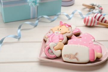 Heart shaped plate of baby shower cookies and accessories on white wooden table
