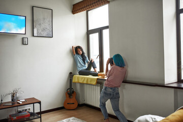 Woman taking photo of her girlfriend near window