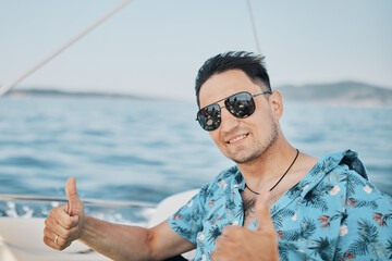 portrait of a happy brunette man in sunglasses on a speedboat laughing