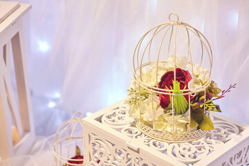Decor. White vintage birdcage. White and red flowers.