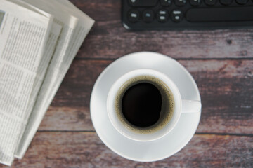 Kaffeebecher Ansicht von oben auf Holzuntergrund, Tastatur und Zeitung im Hintergrund, horizontal