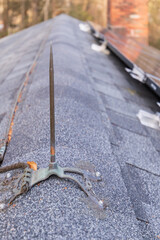 Close up of  lighting rod mounted on a residential roof to ground the structure from lightning damage and fire from static electricity discharge that can severely damage a
 home connect each rod