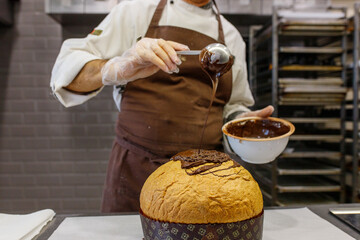 Fototapeta Pasticciere mentre fa colare del cioccolato fondente fuso su un panettone artigianale  obraz