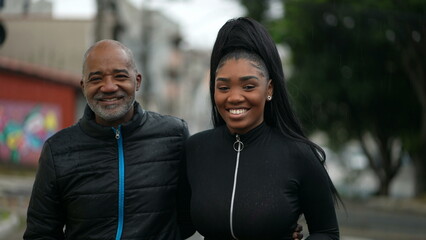 A black father and teen daughter walking together outside in street