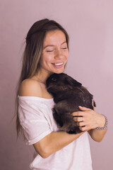 Young woman with adorable rabbit indoors, close up. Lovely pet and animal concept