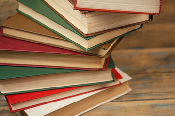 Stack of books on wooden table over rustic background with copy space