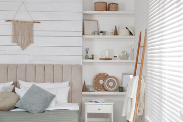 Wall shelves with beautiful decor elements in stylish bedroom interior