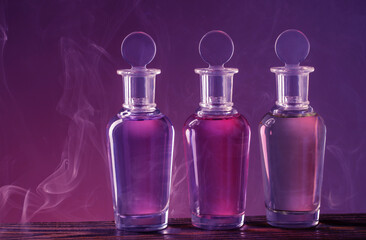 Obraz na płótnie Canvas bottles with magic potion in smoke on purple background