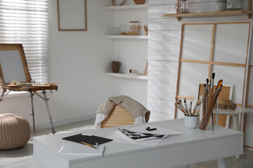 Modern studio interior with artist's workplace and wooden easel
