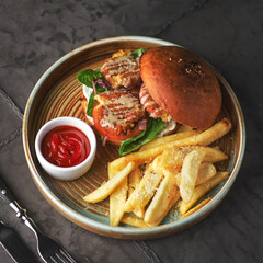 Falafel burger with lettuce, tomato, onion, french fries, spicy fragrant sauce on table. Vegetarian food tasty and nutritious
