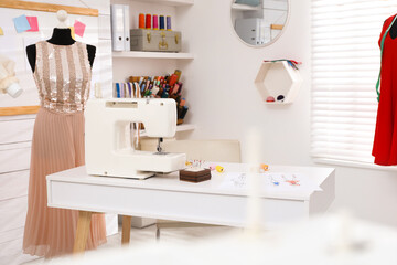 Dressmaking workshop interior with modern sewing machine, mannequin and accessories