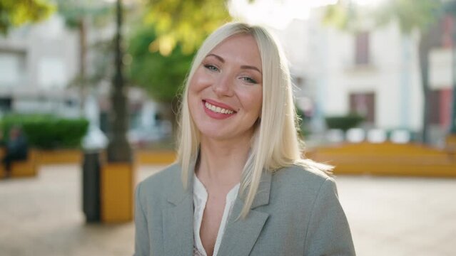 Young blonde woman executive smiling confident standing at park