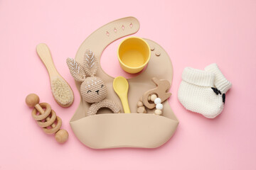Flat lay composition with baby accessories and bib on pink background