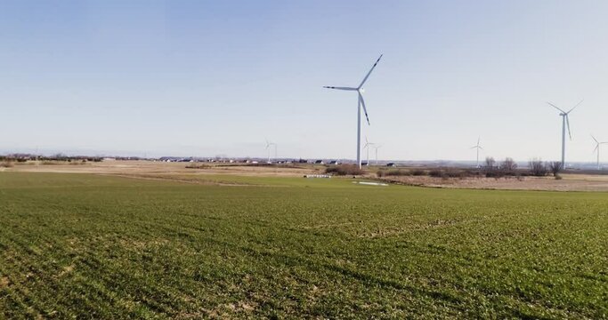Wind turbines in the rape field - aerial footage. Aerial flight at Sunset over windmill WindPark green energy.