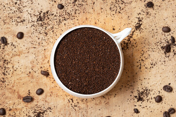 Top view of white coffee cup filled with coffee grounds on wood background