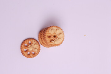 Selective focus of pile of peanut cookies and a piece of biscuit, white background front view